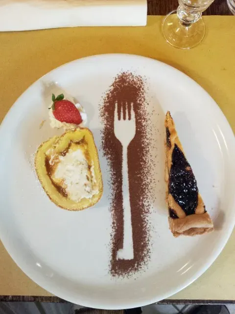 Creative dessert plate with a cocoa powder fork stencil and two pastries.