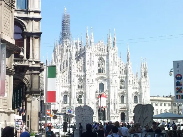 Duomo di Milano towering over a bustling square—Gothic spires, marble brilliance, and Expo banners marking the moment.