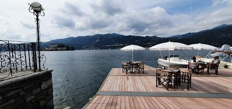 A wooden dock with tables and chairs and umbrellas next to a body of water.