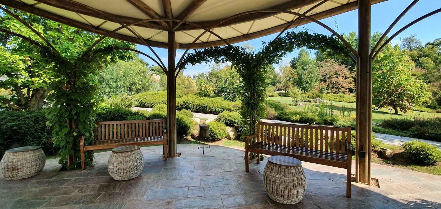 There are two benches under a gazebo in the park.