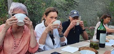 A group of people are sitting at a table drinking from cups.