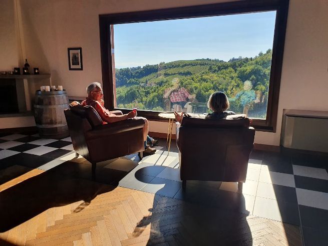 Two people are sitting in chairs in front of a large window.