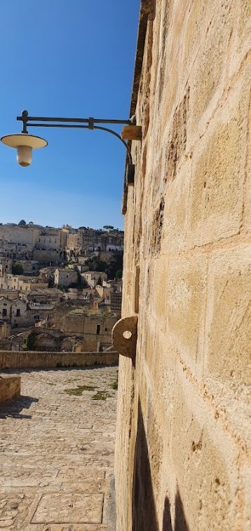 A brick wall with a lamp on it and a city in the background.