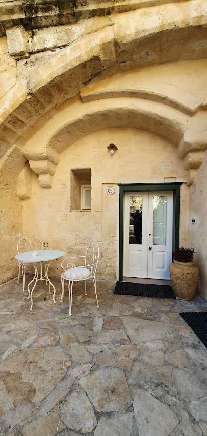 A stone patio with a table and chairs in front of a stone building.