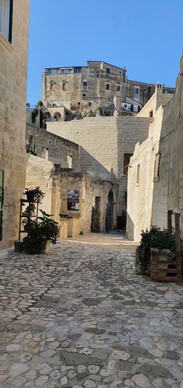 A stone alleyway between two buildings with a castle in the background.