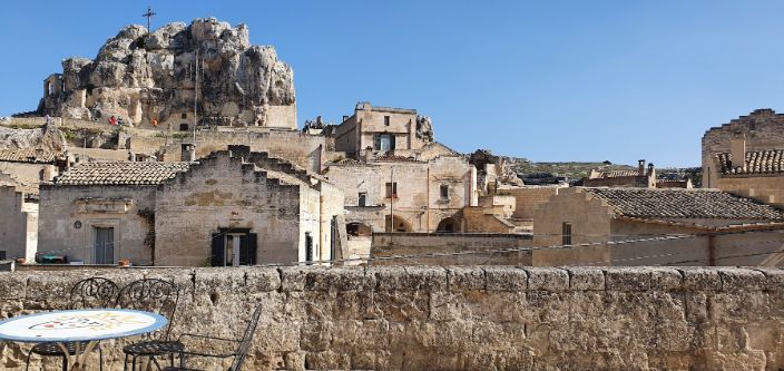 There is a table and chairs in front of a stone wall with a mountain in the background.