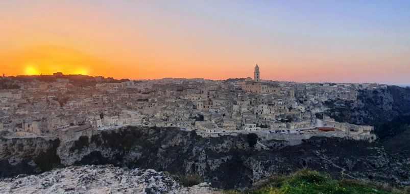 The sun is setting over a city on a hill.