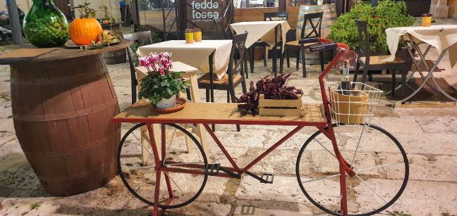 A red bicycle is sitting on a table in front of a restaurant.
