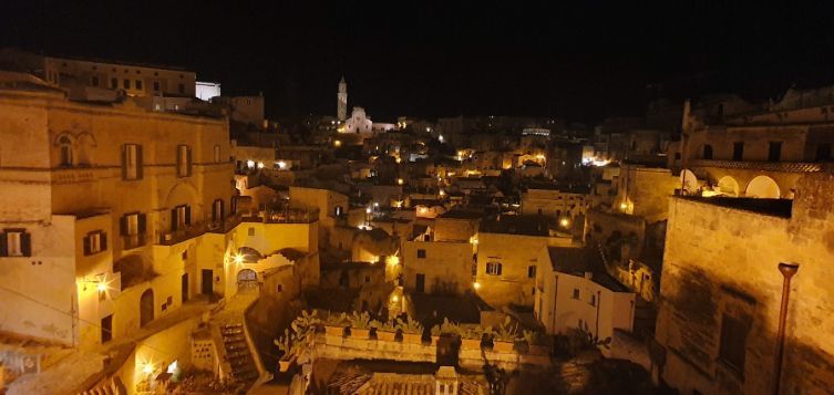 An aerial view of a city at night with buildings lit up.