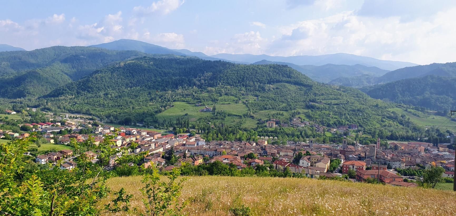 A view of a city from a hill with mountains in the background.