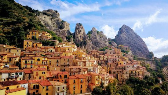 A small town on top of a hill with a mountain in the background.