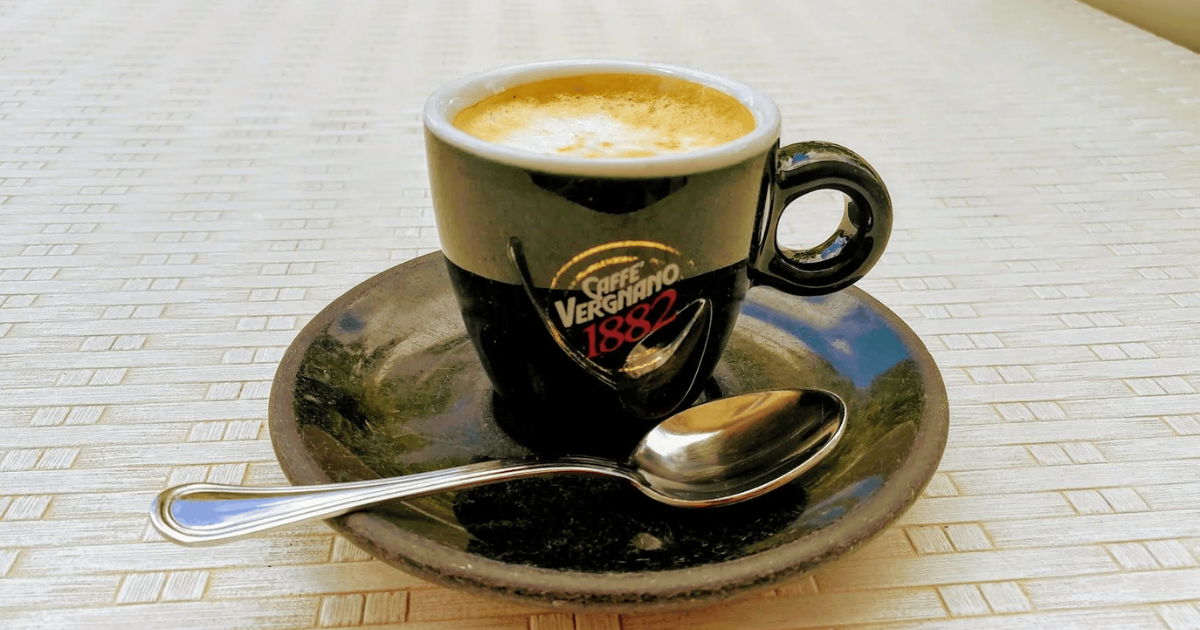 Cup of Caffè Vergnano espresso on a saucer atop a tiled table.