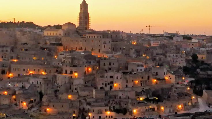 An aerial view of a city at sunset with a clock tower in the background.