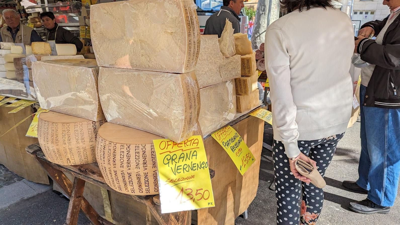A woman is standing in front of a display of cheese.