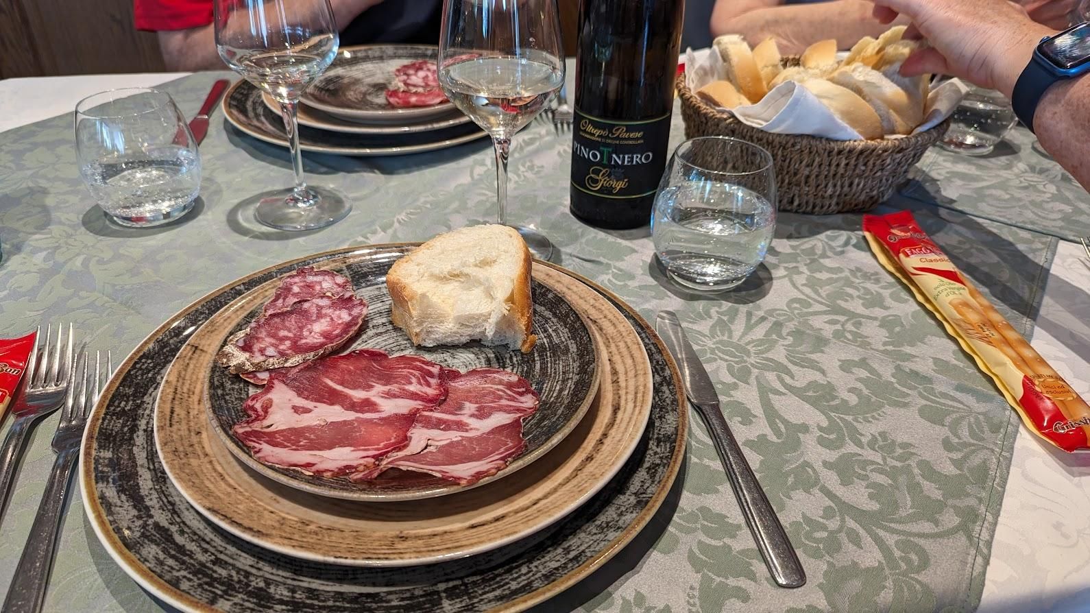 A table with plates of food and a bottle of wine on it.