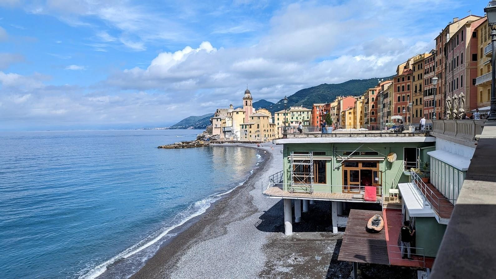A beach with a green building in the foreground and a city in the background.