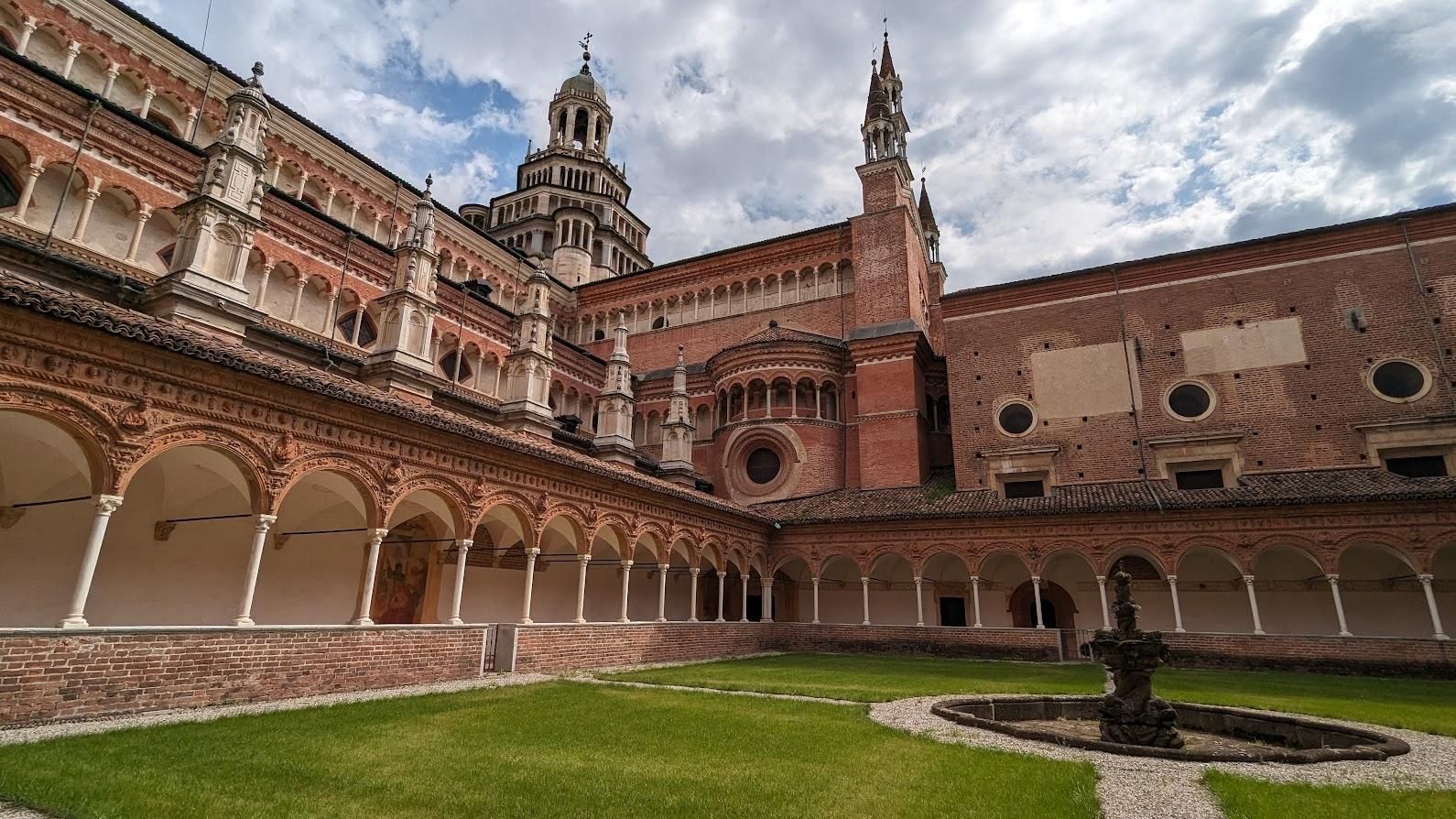 A large brick building with arches and a fountain in front of it.