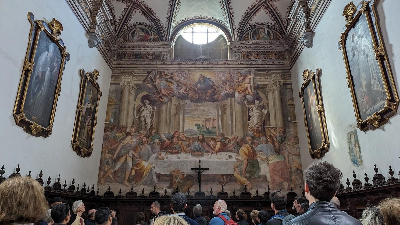 A group of people are standing in front of a large painting in a church.