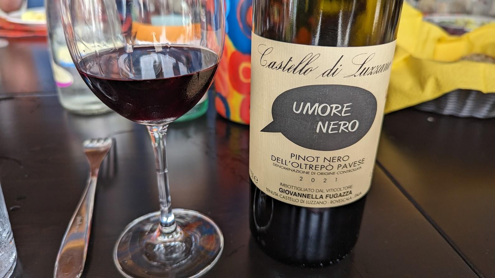 A bottle of wine and a glass of wine are on a table.