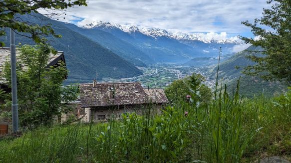 There is a house in the middle of a valley with mountains in the background.