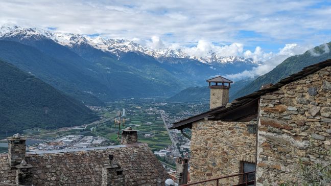 A stone building with a chimney in front of a mountain range.