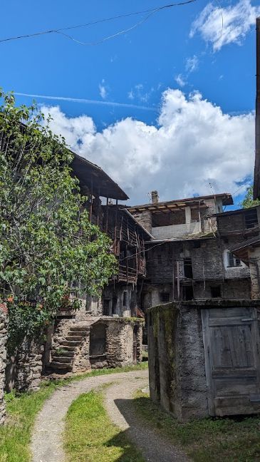 A dirt road leading to a stone building with a blue sky in the background.
