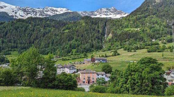 A small village in the mountains with a waterfall in the background.