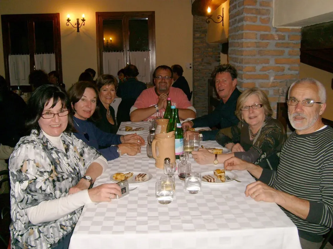 Group enjoying dinner at a long table in a cozy Italian restaurant.