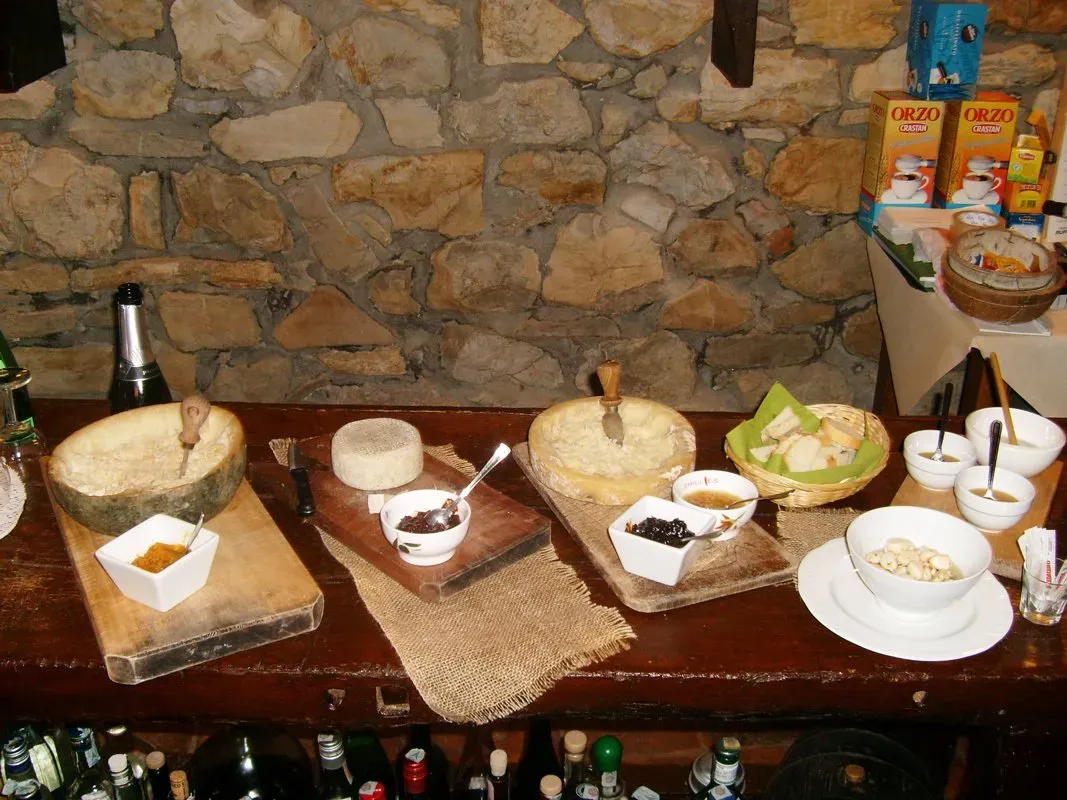 Cheese and jam tasting spread on a rustic wooden counter with a stone wall backdrop.