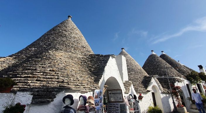 A group of people are standing in front of a building with a roof that looks like a pyramid.