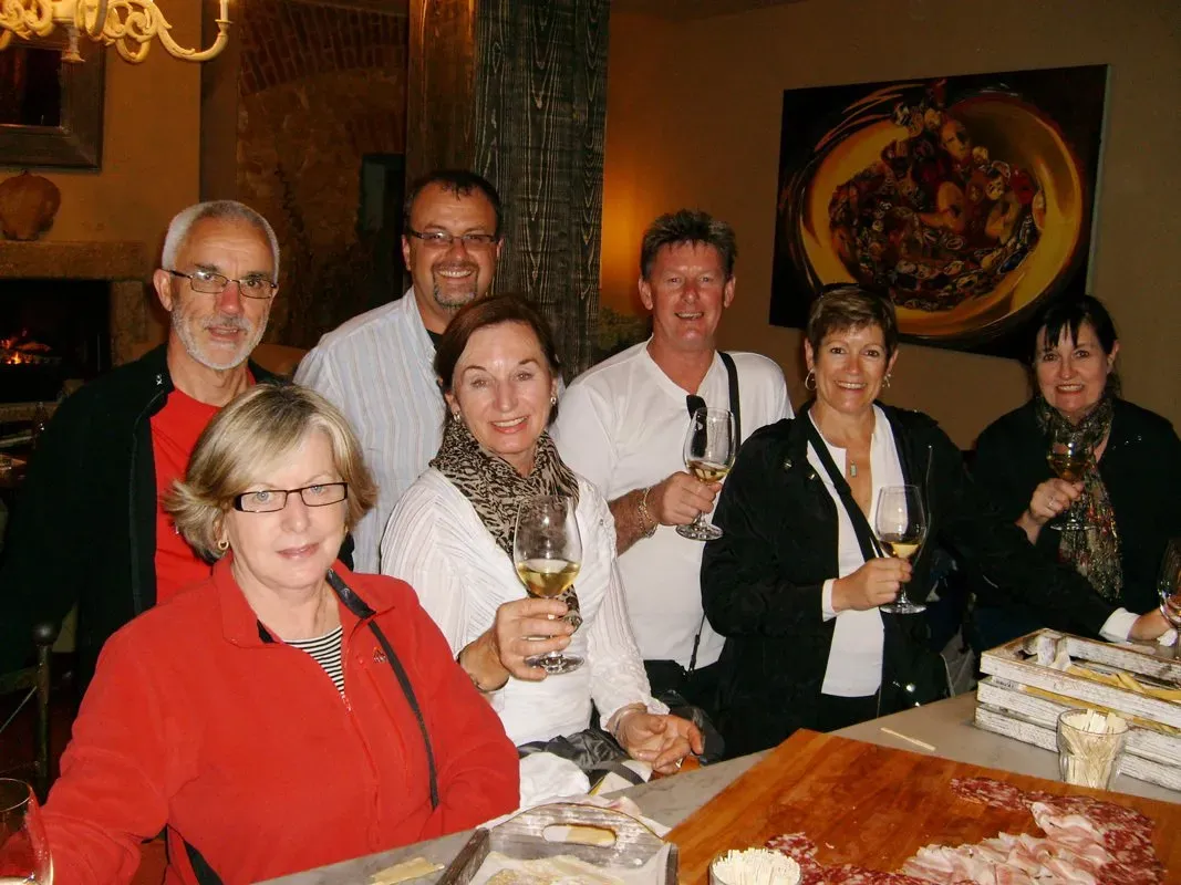 Group of people enjoying wine and cured meats during a tasting in a cozy indoor setting.