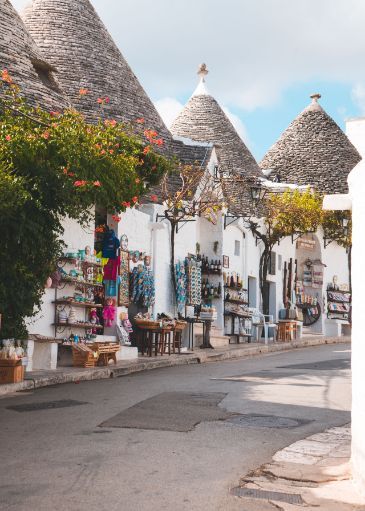 A row of white buildings with a thatched roof are lined up on a street.