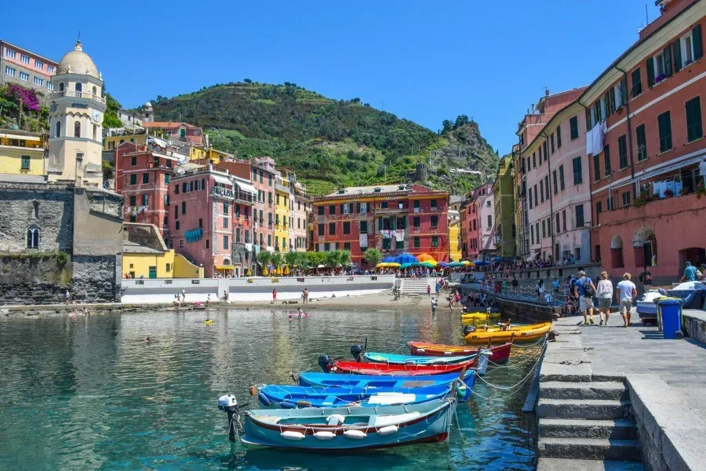 Vernazza harbor with colorful boats and pastel buildings.