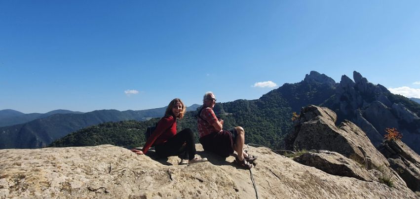 Two people are sitting on top of a rocky mountain.