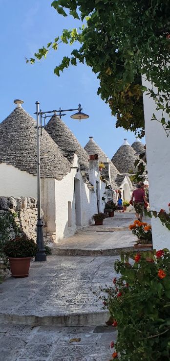 A narrow street with a row of white buildings and a lamp post.