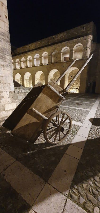 A wooden cart is parked in front of a building at night.