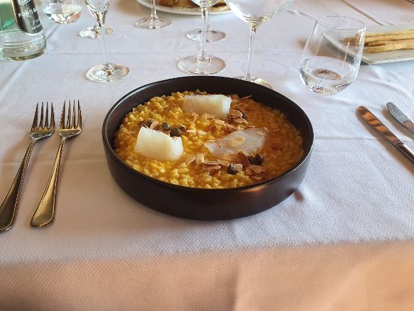A bowl of food on a table with forks and knives