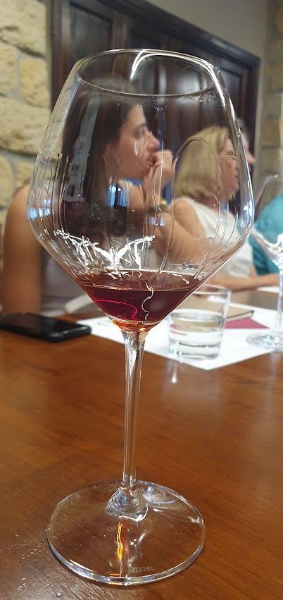 A glass of red wine is sitting on a wooden table.