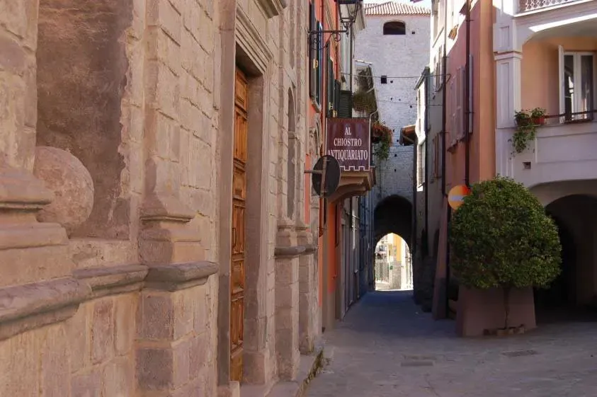 Narrow cobblestone alley lined with stone and pastel buildings in an old Italian town.