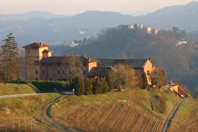 A large building is sitting on top of a hill with mountains in the background.