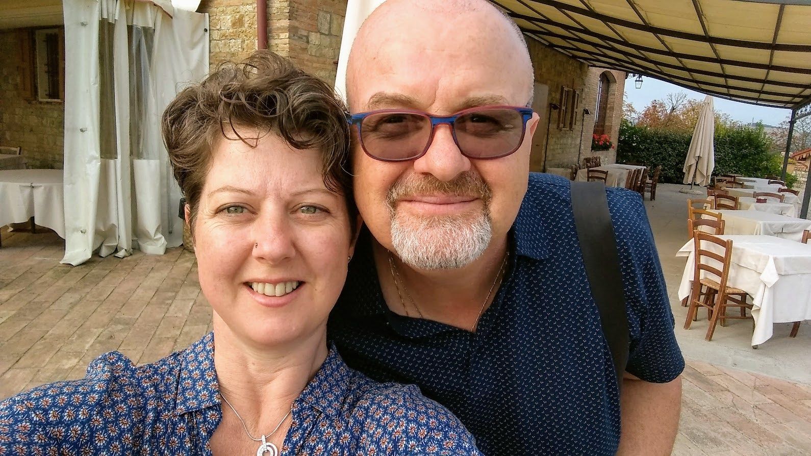 A man and a woman are posing for a selfie in front of a restaurant.