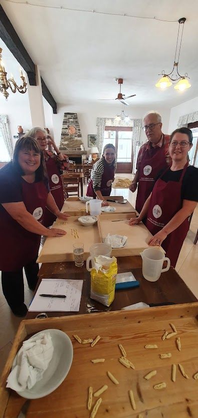 A group of people are standing around a table making pasta.