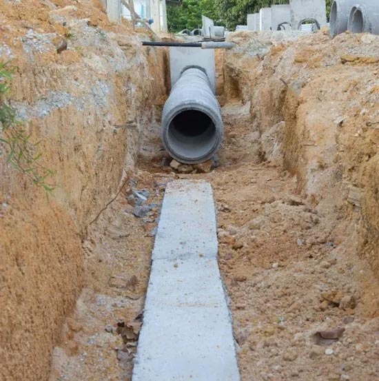 A concrete pipe is being installed in a trench.
