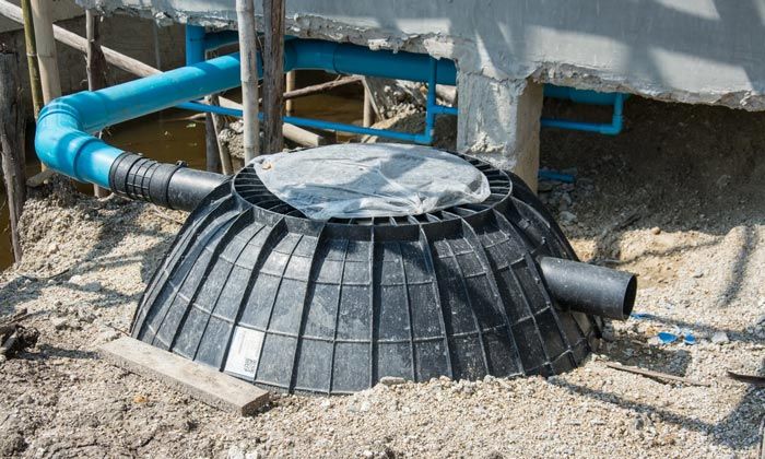 A septic tank is sitting in the dirt next to a building.