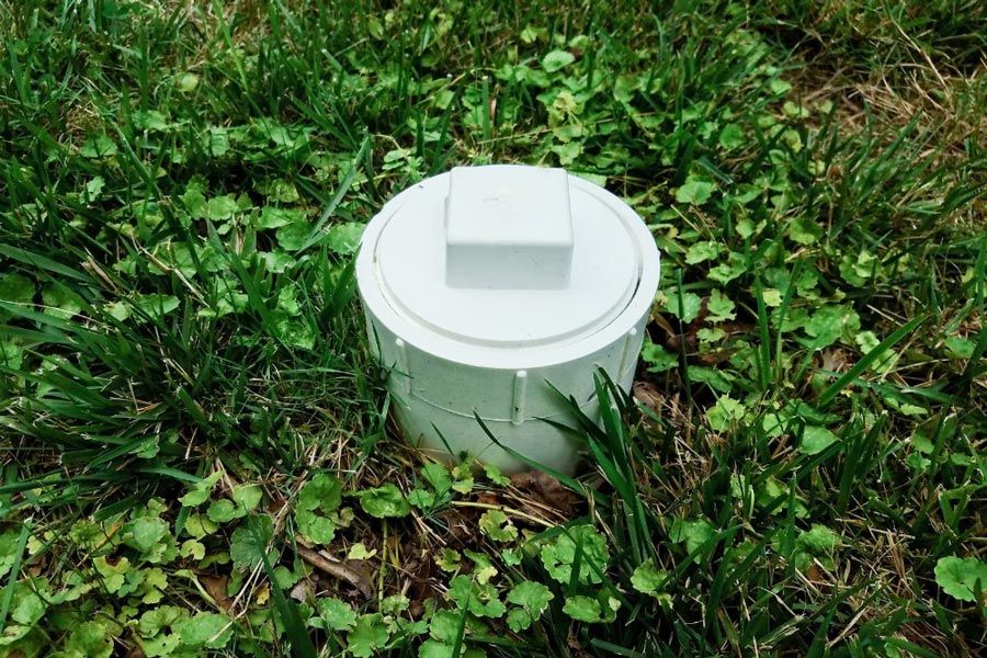 A white pvc pipe is sitting in the grass.