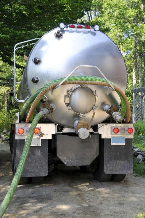 A septic tank truck with a green hose attached to it.