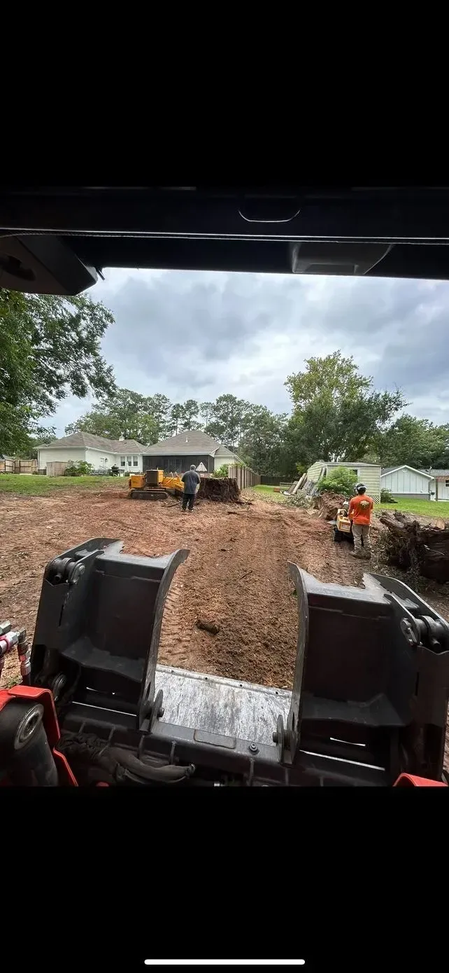 Construction site with equipment and workers in action, on a cloudy day.