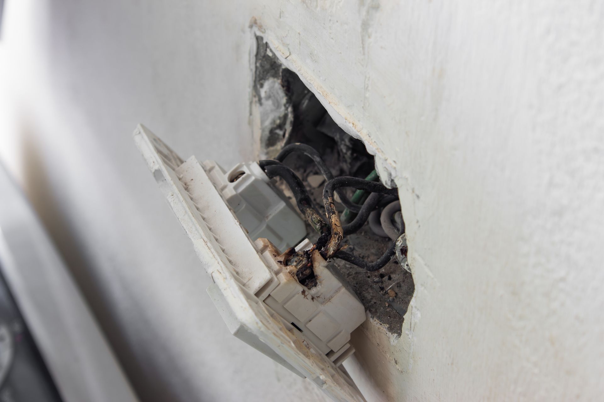 A light switch is sitting in a hole in a wall.