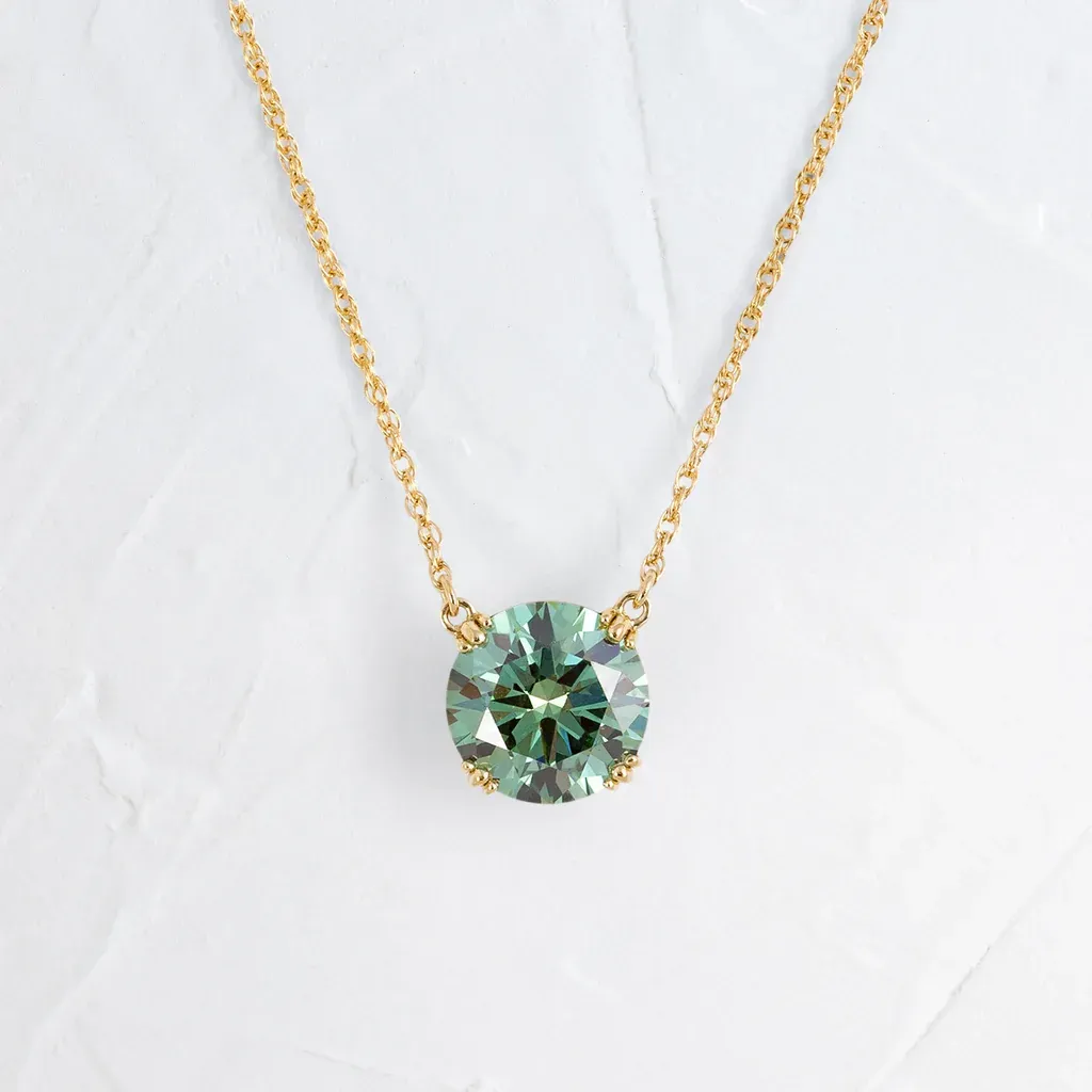 Gold necklace with a large, round green gemstone pendant.