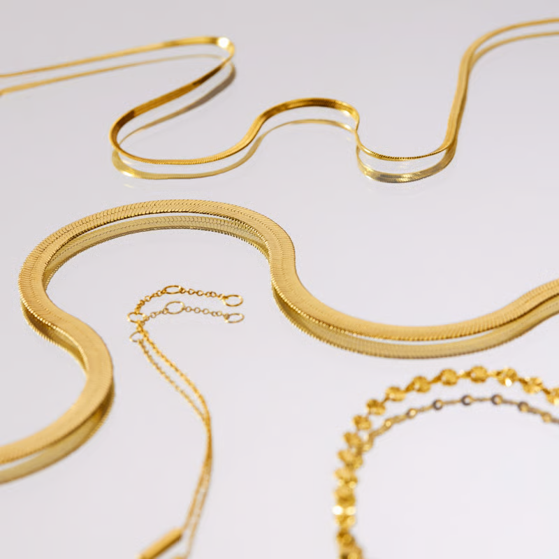 Gold necklaces on a blue background, various chain styles displayed.